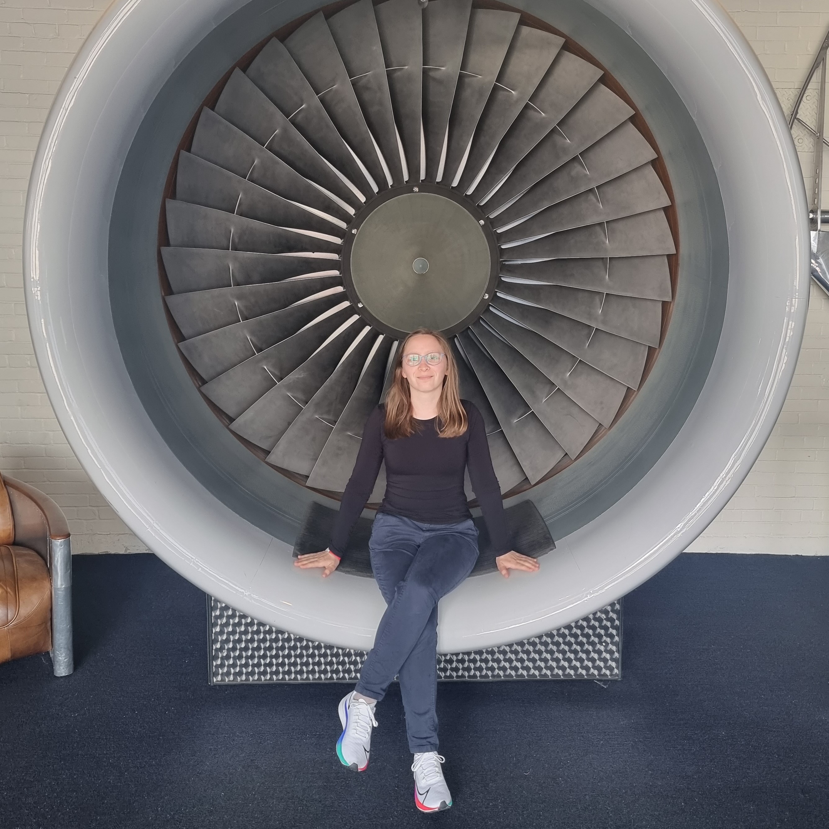 A photograph of Ana Rebeka Kamšek, sitting in a plane engine.